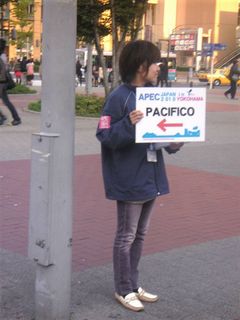 桜木町駅前でAPECの案内板を持つ女性